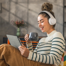 Podcast Thumbnail: A woman with headphones sips coffee on a couch, creating a cozy atmosphere